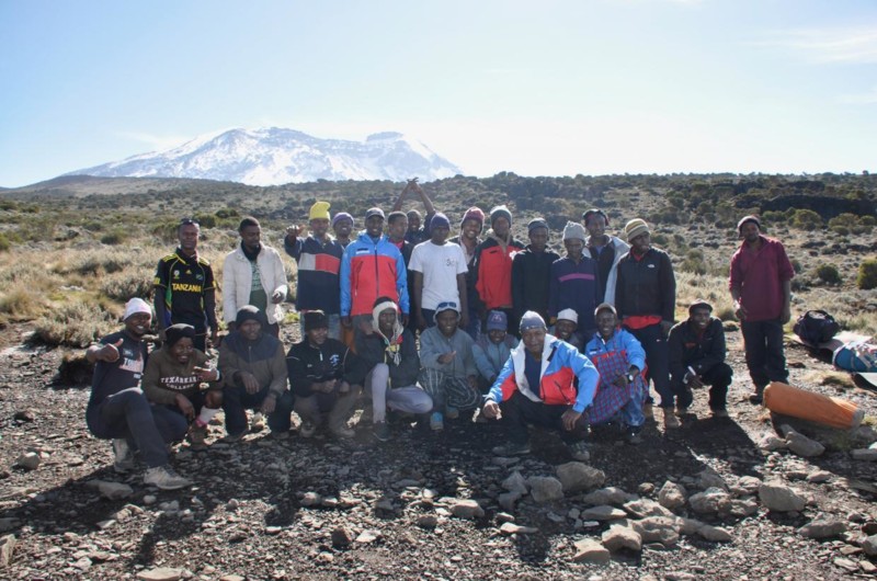 Guider och medhj&auml;lpare p&aring; v&auml;g upp mot Kilimanjaro